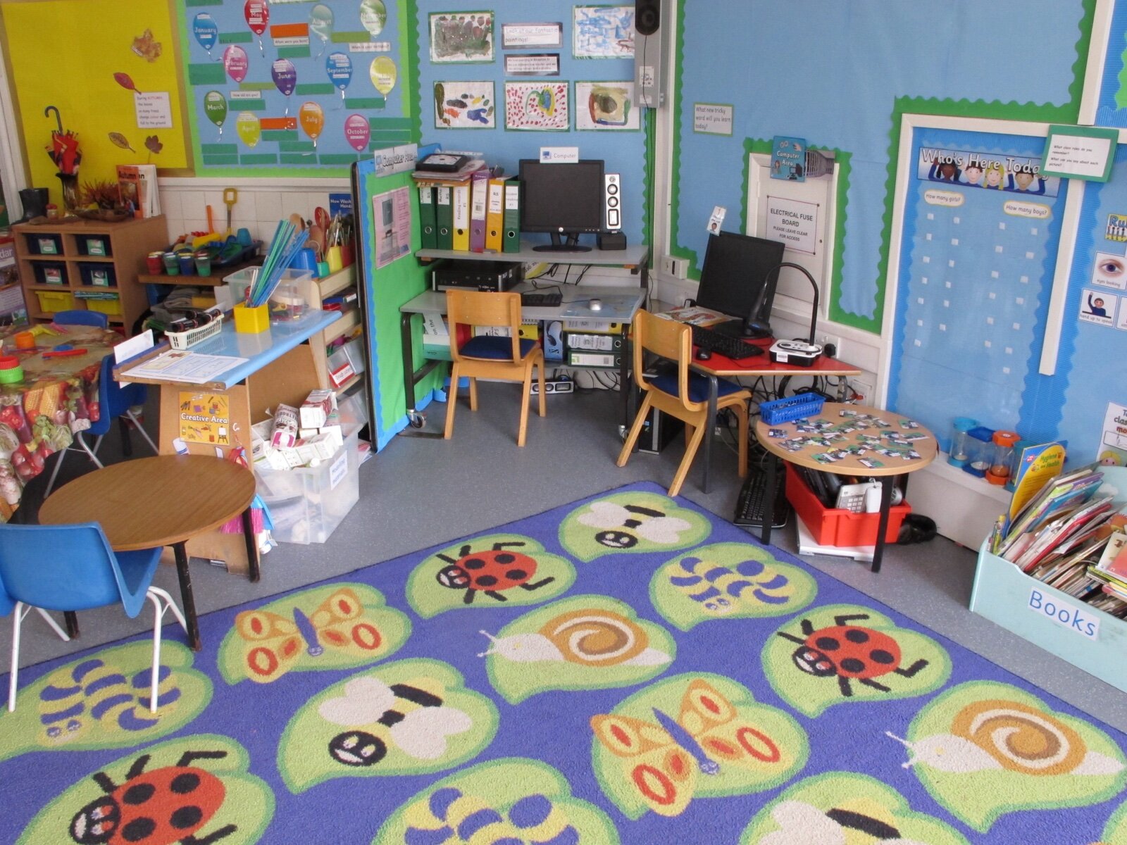 A primary school classroom with a reading corner, computer area and low tables set out for young children