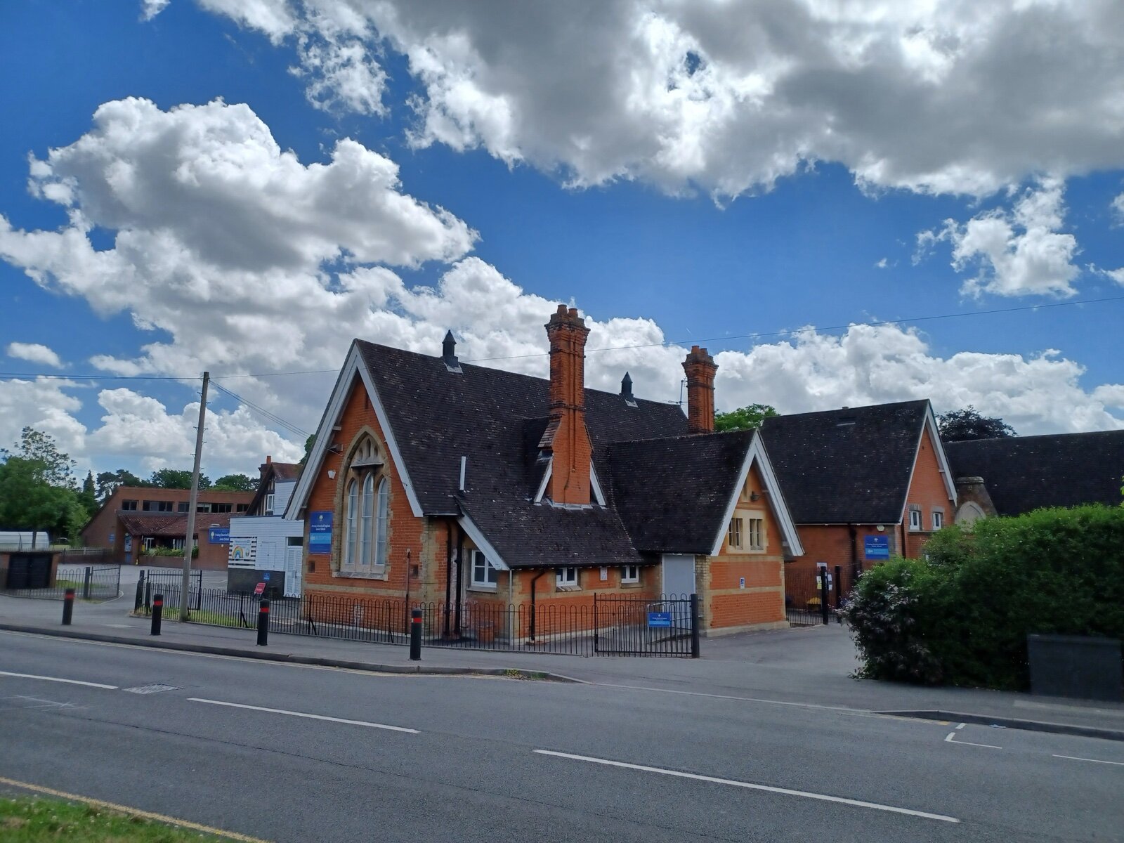 A Church of England junior school building in England, redbrick with gabled roofs, seen from the roadside
