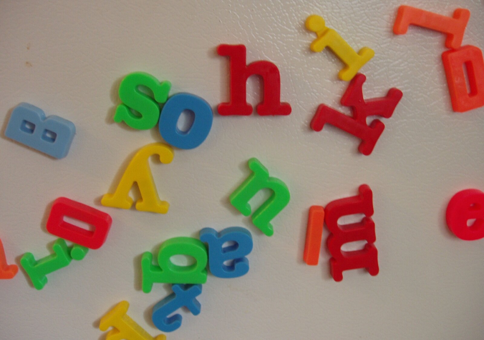 Coloured plastic magnetic letters scattered on a fridge door