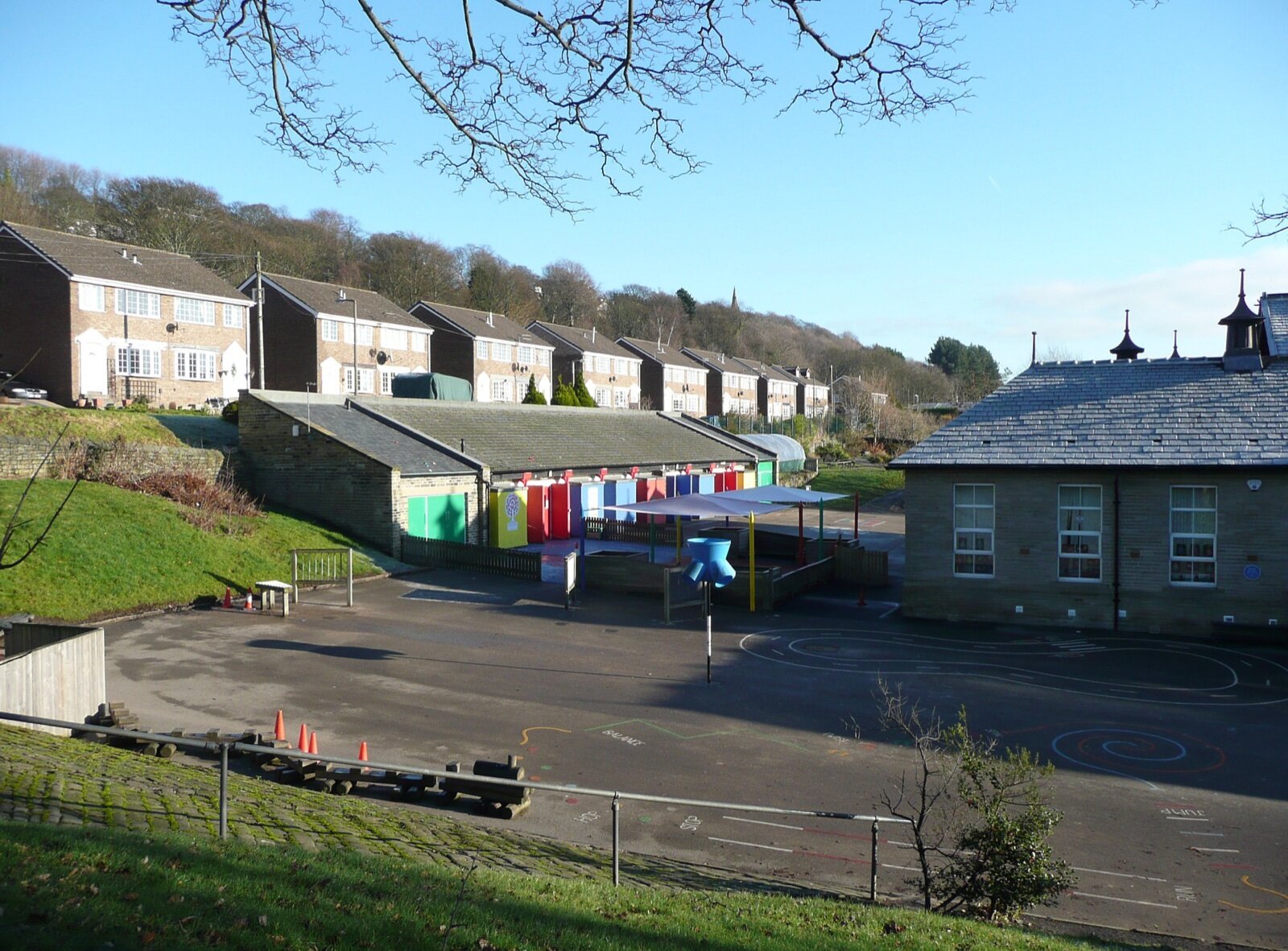 An empty English primary school playground with markings, a shelter and classroom blocks