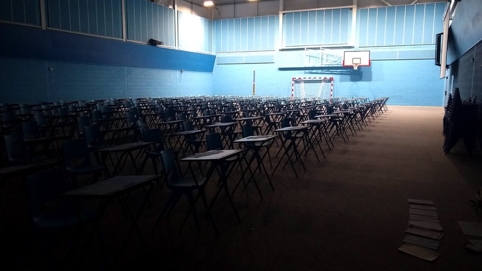 A school sports hall laid out in rows of exam desks