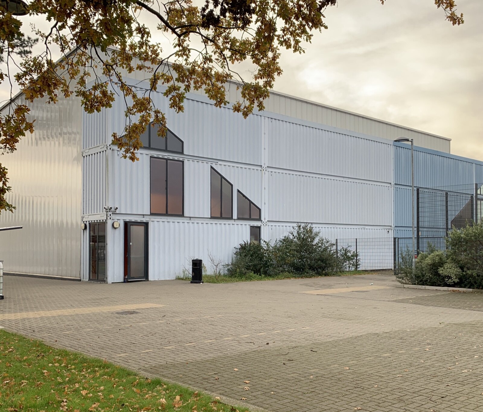 White clad sports hall at Dunraven School in Streatham under autumn oak leaves